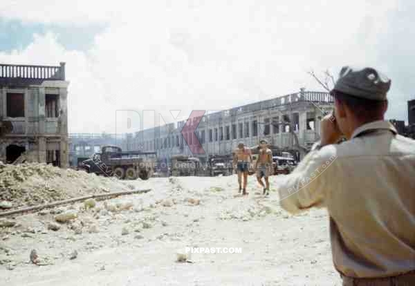 American GMC Jimmy cargo trucks parked outside a blown up Japanese government building. Naha Okinawa 1945