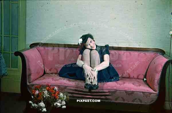 Beautiful wife in evening costume waiting on sofa in Berlin apartment. 1939
