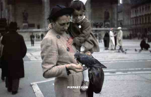 Mother feeding birds with daughter in Odeonsplatz in Munich, Germany 1938, behind Feldherrnhalle,