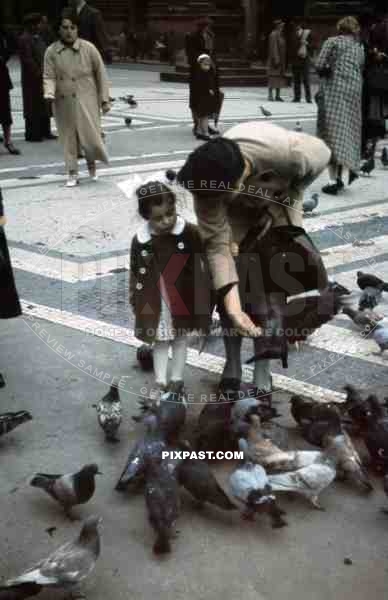 Mother feeding birds with daughter in Odeonsplatz in Munich, Germany 1938, behind Feldherrnhalle,