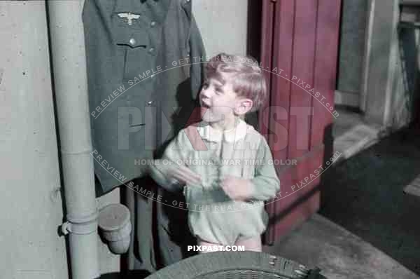 Munich, Germany, 1940. Son of wehrmacht soldier plays with dads army uniform in Munich apartment.