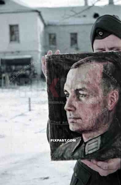 Wehrmacht soldier holding up a portrait painting of a military Doctor at the monastery in Syrkovo, Russia 1941