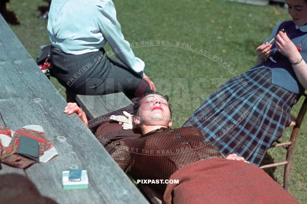 Beautiful Austrian women resting in the sun. Lighter and Cigarettes on her table. Red pattern dress, Lip Stick.